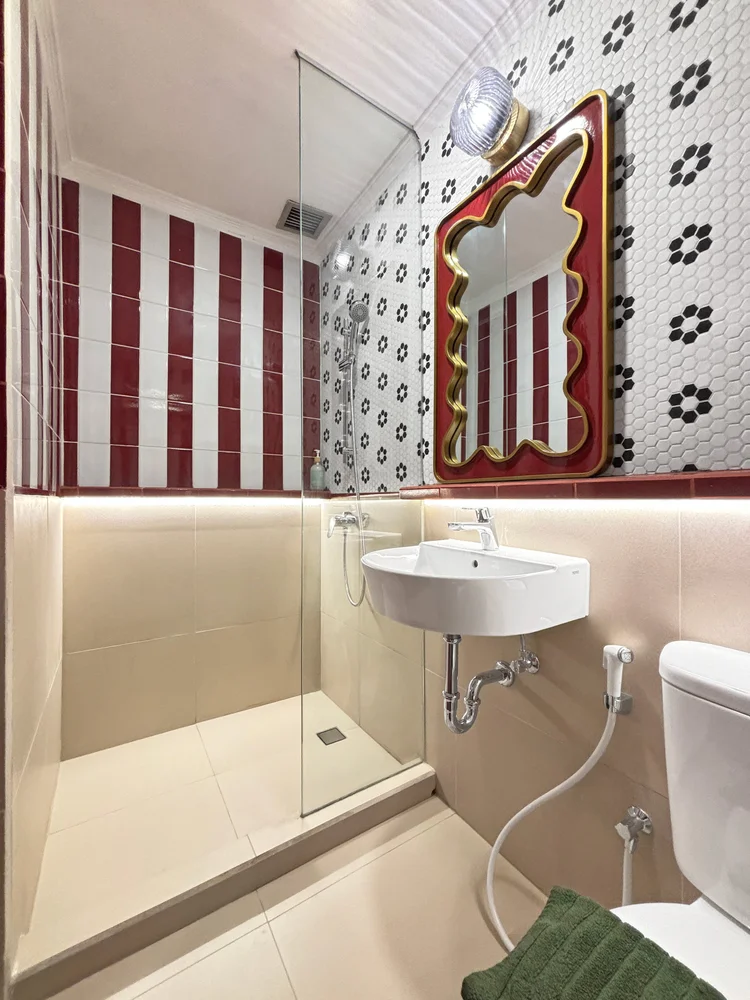 Chamonix: Bathroom with a cherry-print mirror; soap and shampoo already stocked, the same in every unit.