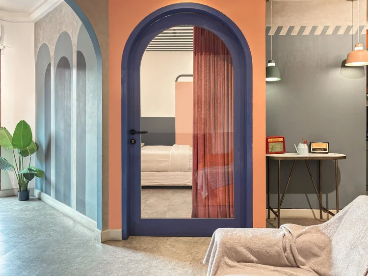 Geneva: A curtained arch leads to the bedroom, with a plant in the corner.
