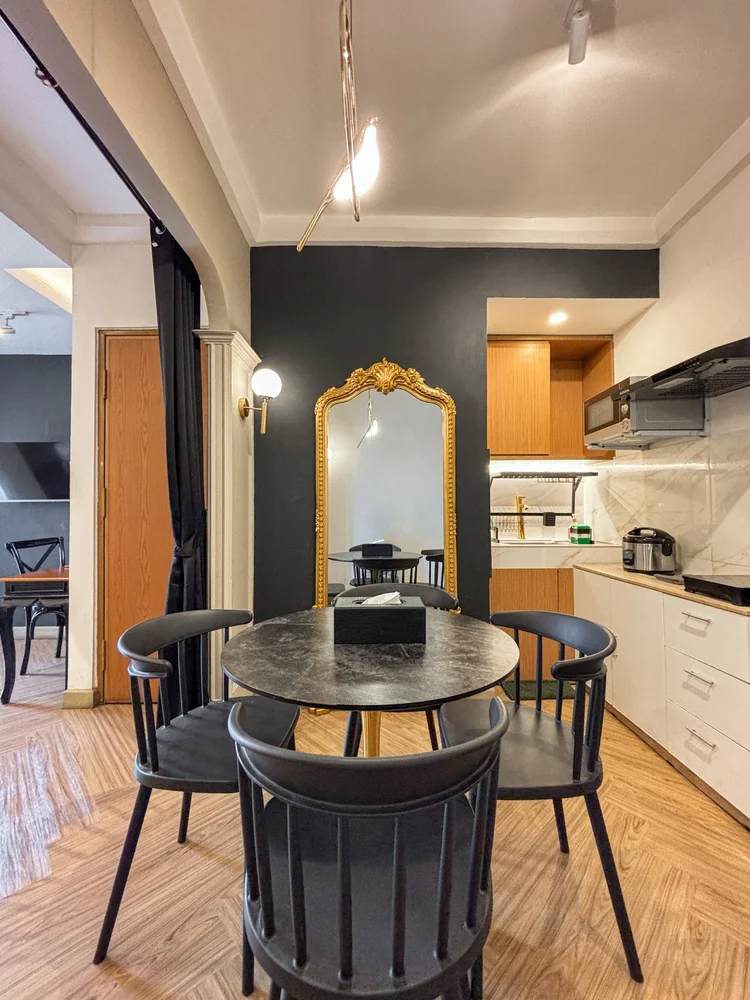 Vienna: A round dining table with a gold-framed mirror, the open kitchen just beyond.