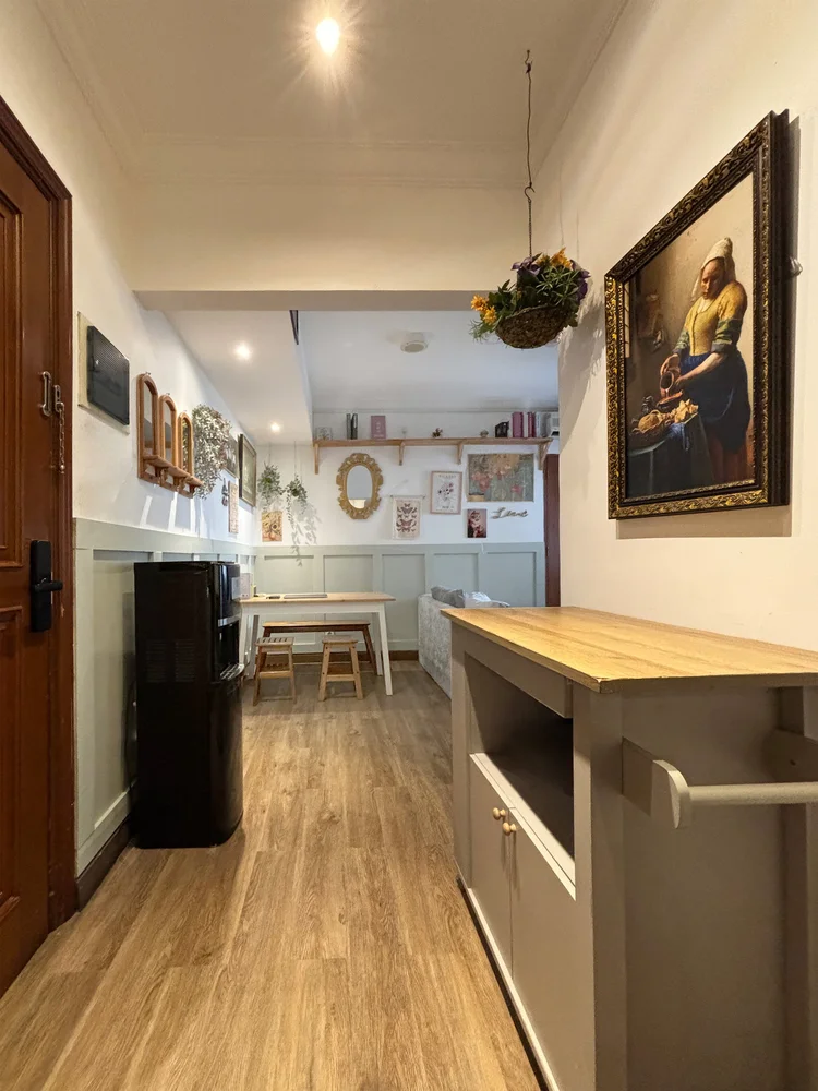 Florence: A hallway with a mirror and framed art, linking the living room to the bedrooms.