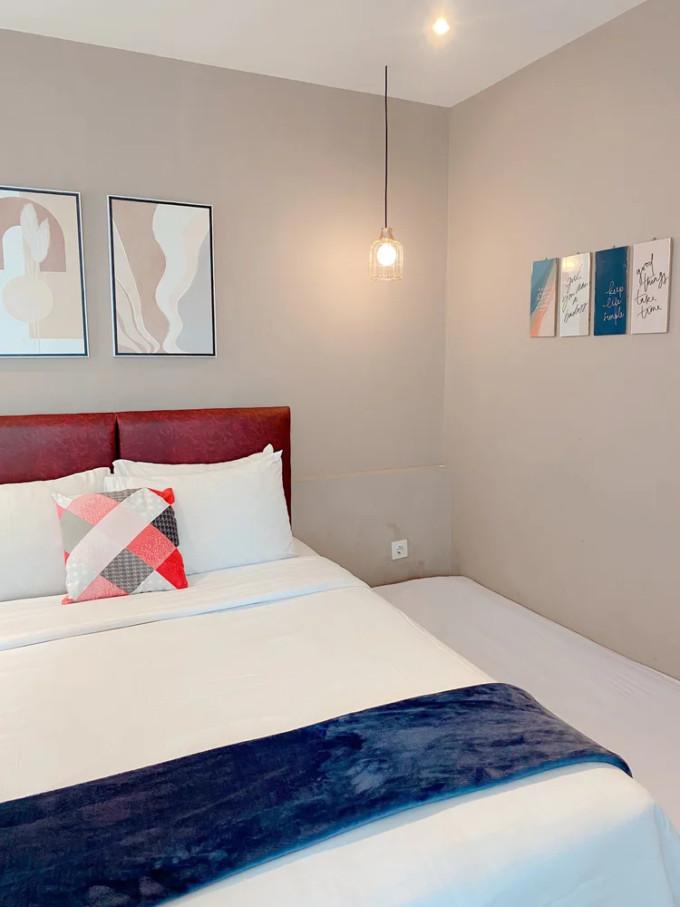 Oslo: Bedroom with a maroon headboard and a hanging lamp on each side.
