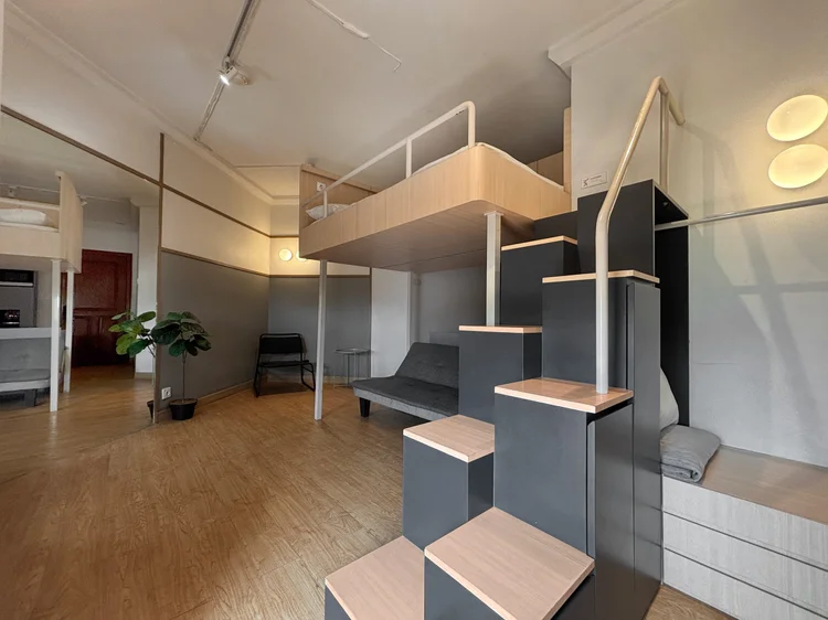 Den Haag: The stairs and safety rail up to the loft bed, with AC and a plant in the corner.