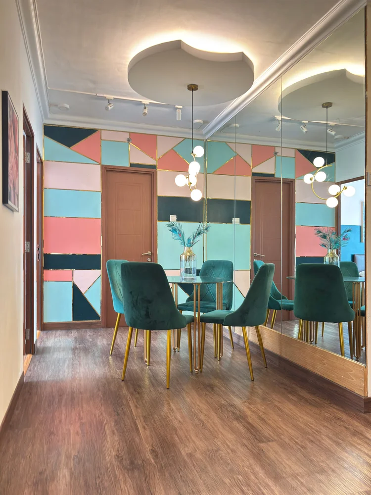 Beverly: Dining table for four with teal chairs, a mirrored wall behind it.