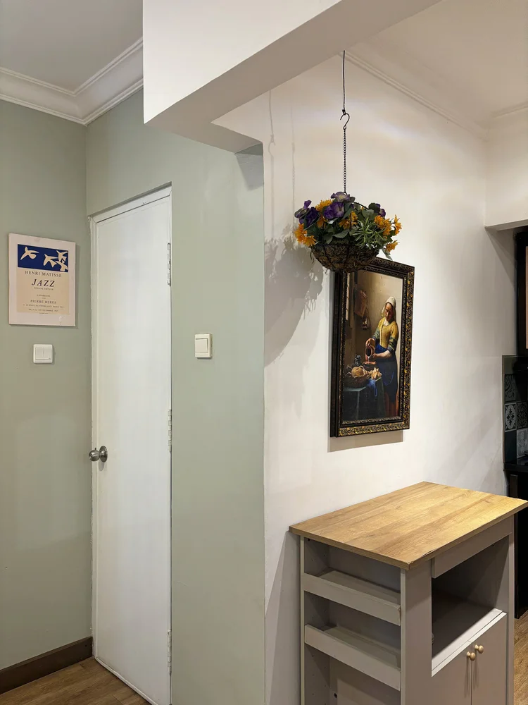 Florence: An arch into the hallway, with a hanging plant and a small gallery of frames.