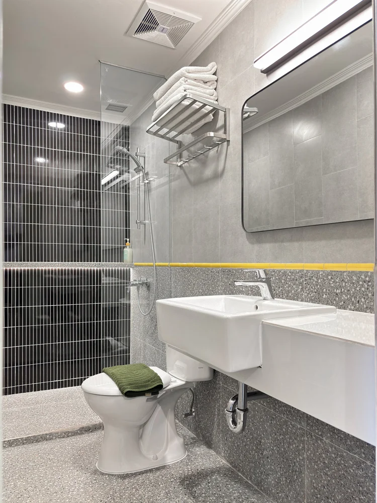 Dae Jeon: Bathroom with platform-style yellow stripes, and a hot shower.