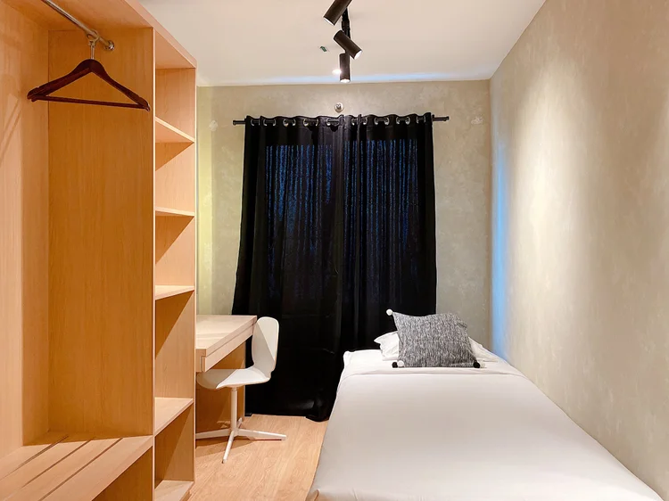 Amalfi: A single bed with an open wardrobe and its own table, comfortable for one.