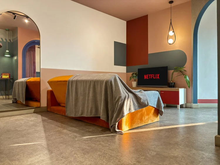 Geneva: The bed with a mustard throw, with the smart TV on Netflix visible from the room.