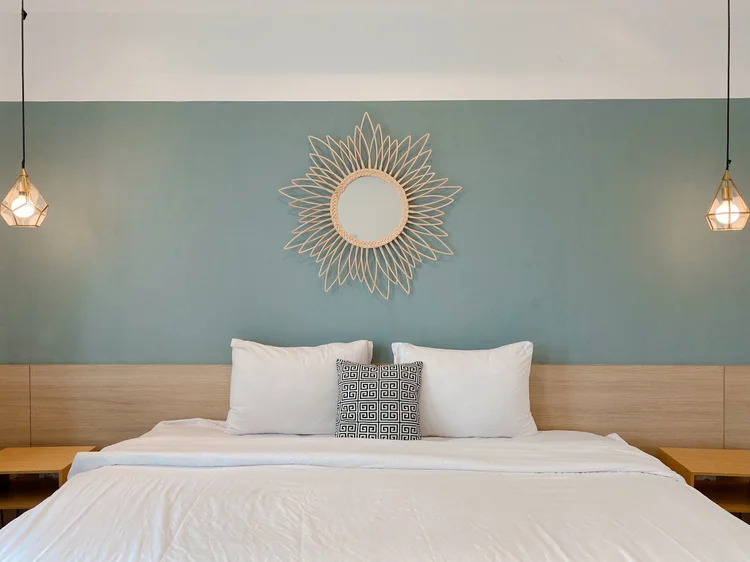 Oslo: Bedroom with a 200 cm king bed and a sunburst mirror on a green wall.