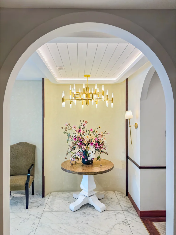 Kensington: The entry foyer with a chandelier and round table, a grand first impression.
