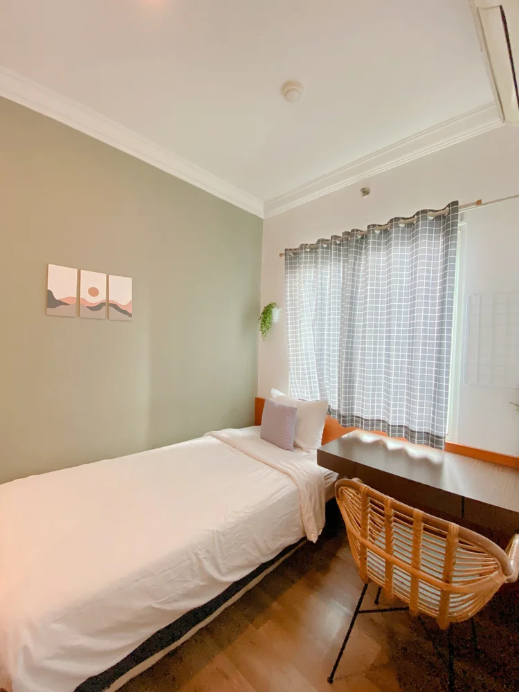 Oslo: A single bed by the window with a table and rattan chair.
