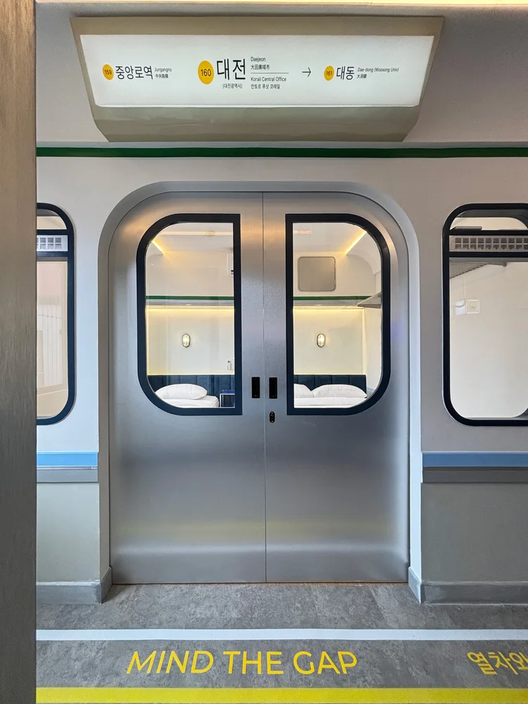 Dae Jeon: Subway-style doors with a Mind the Gap decal, a small nod to the station theme.