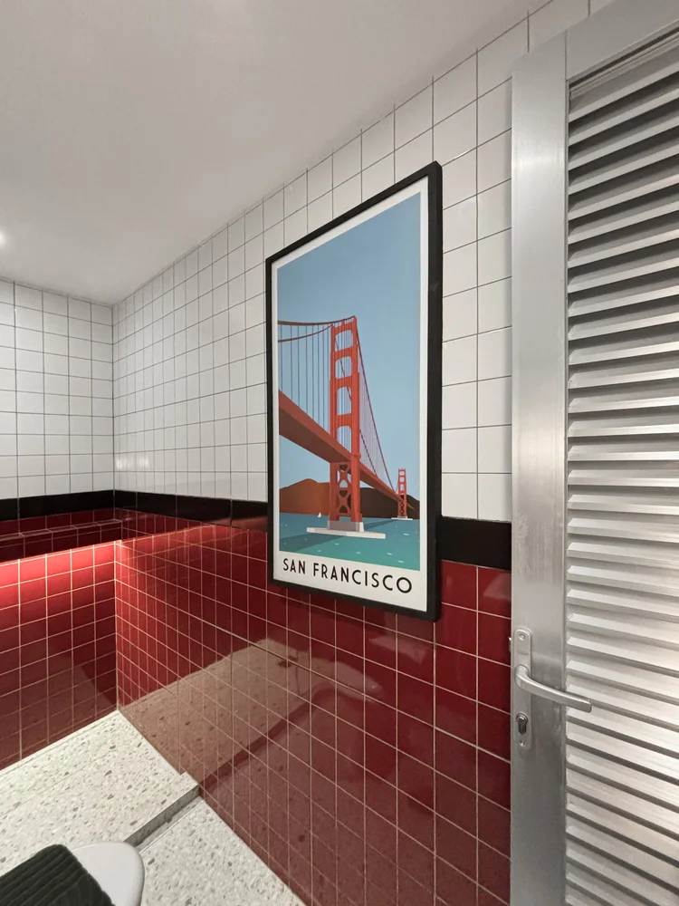 San Francisco: A Golden Gate poster on the bathroom door, red tiles continuing inside.