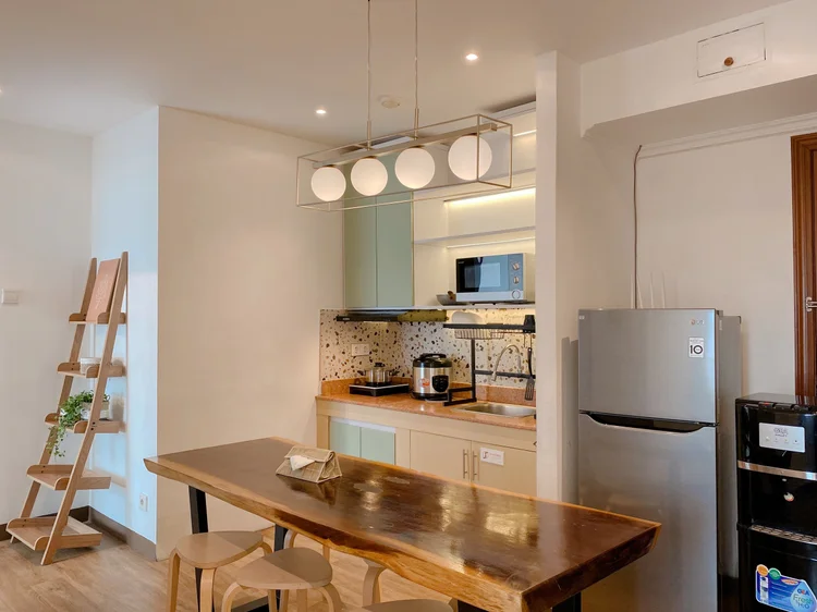 Positano: A wooden dining table for six, the open kitchen and fridge behind it.