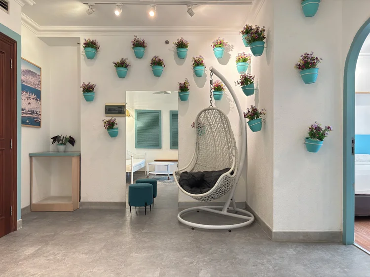 Mykonos: A hanging chair in the corner of the living room, under the blue flower pots.
