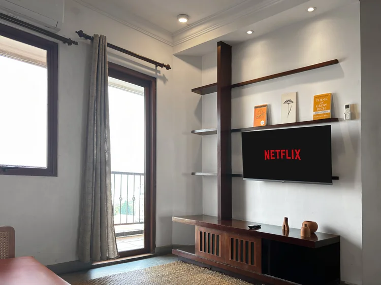 Ubud: Living room with a door to the balcony and a smart TV with Netflix on the wall shelf.