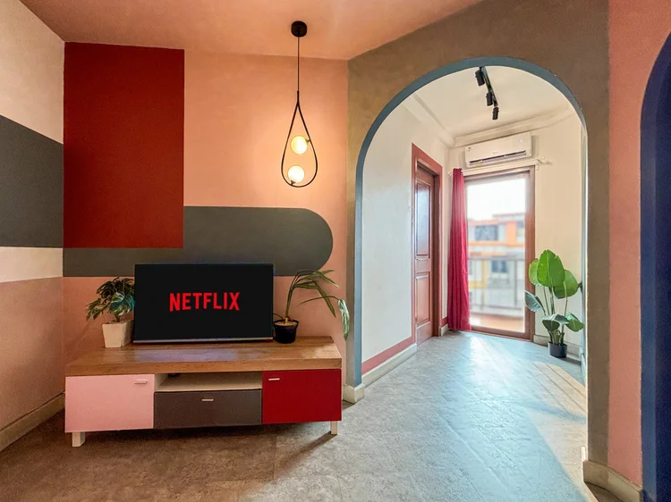 Geneva: Smart TV with Netflix on the pink console, facing the orange sofa.