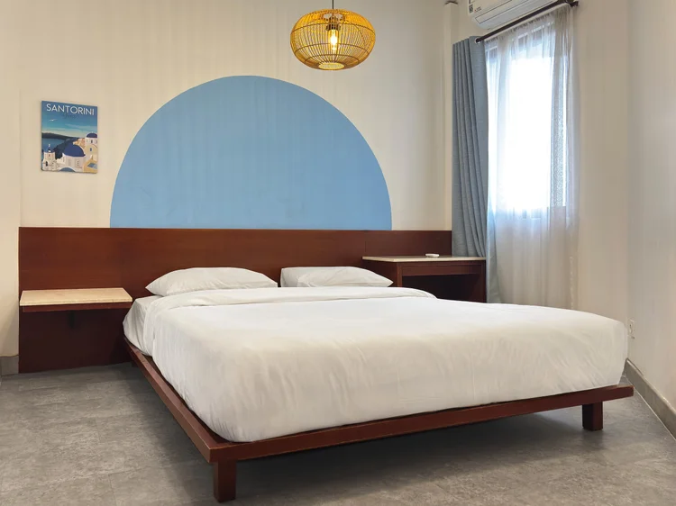 Santorini: A bedroom with a queen bed on a wood base and a blue arch on the wall.