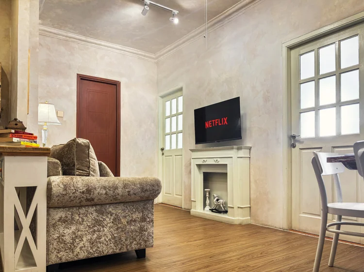 Bordeaux: Three-seater sofa facing the smart TV with Netflix, ceiling fan above.