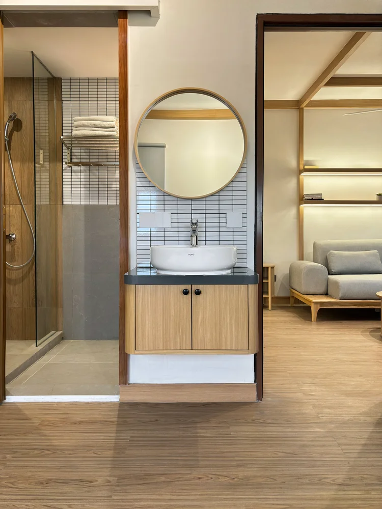Nara: Bathroom with a round mirror and a glass-screened shower.