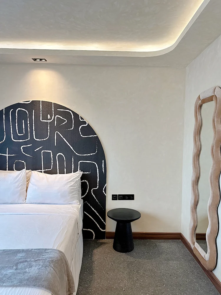 New York: An arched headboard with a graphic pattern, a small table beside the bed.