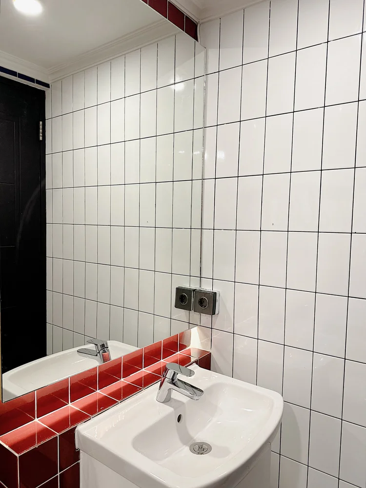 Berlin: Washbasin and mirror, in Bauhaus white tiles with black grout.