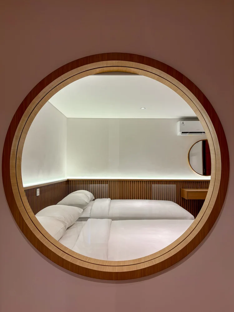 Shizuoka: A round wood-framed mirror, white sheets as in all our units.